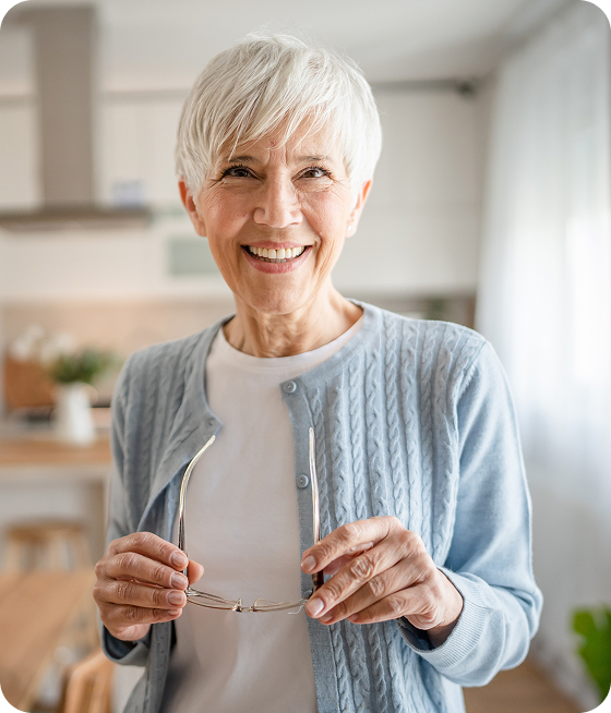 Femme senior souriante tenant ses lunettes